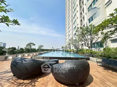 Luxurious high-rise apartment with stunning poolside view and modern outdoor seating.