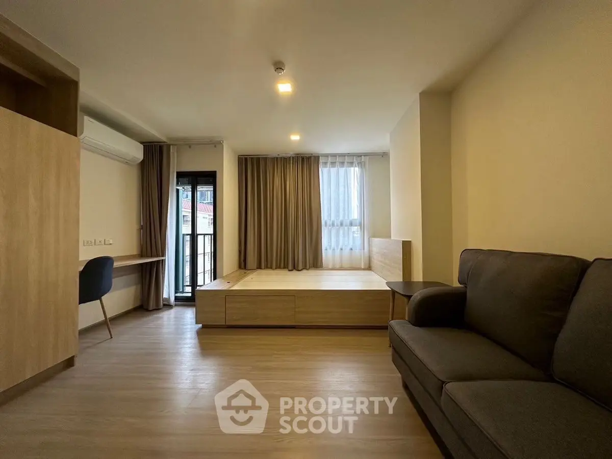 Modern studio apartment with cozy living area and balcony access.