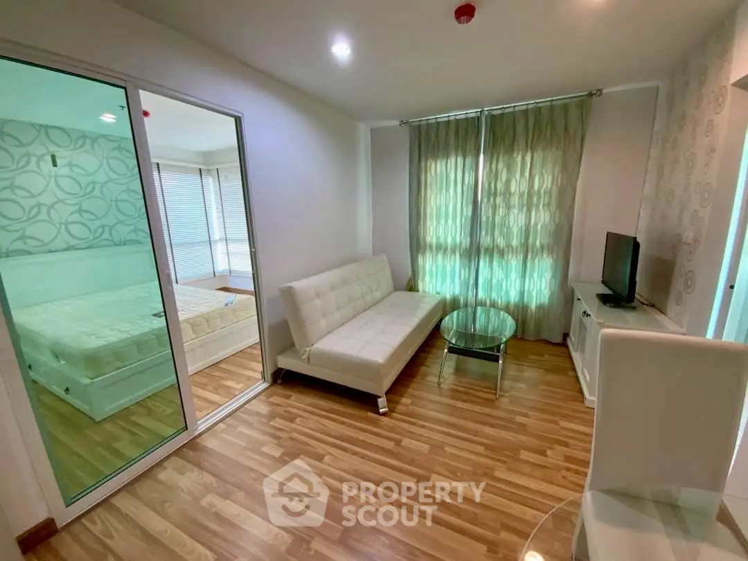 Modern living room with wooden flooring and glass partition to bedroom