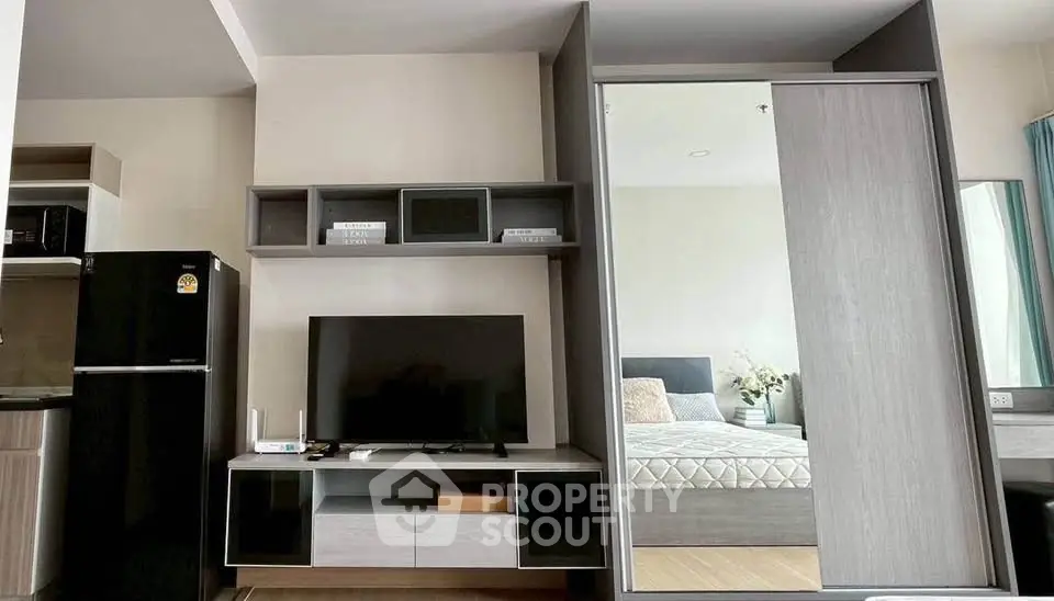 Modern living room with sleek furniture and a glimpse of a cozy bedroom