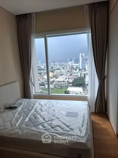 Cozy bedroom with stunning city view from large window, featuring elegant curtains and a comfortable bed.