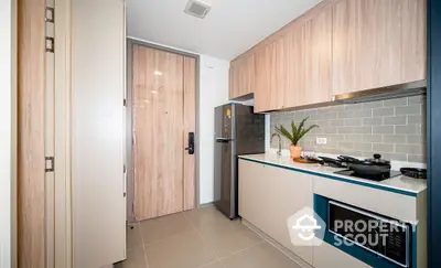 Sleek modern kitchen with stainless steel appliances, light wood cabinetry, and stylish subway tile backsplash in a cozy urban apartment.