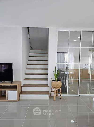 Modern interior with sleek staircase and glass sliding doors leading to kitchen