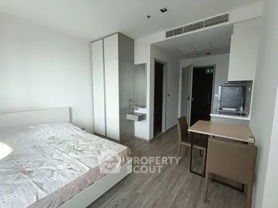 Modern bedroom with integrated kitchenette and dining area, featuring sleek design and ample natural light.
