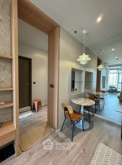 Modern apartment interior with stylish dining area and cozy living room, featuring elegant lighting and wooden accents.