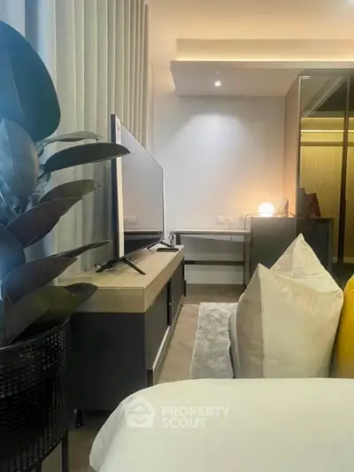 Modern bedroom with sleek TV stand, cozy pillows, and ambient lighting.