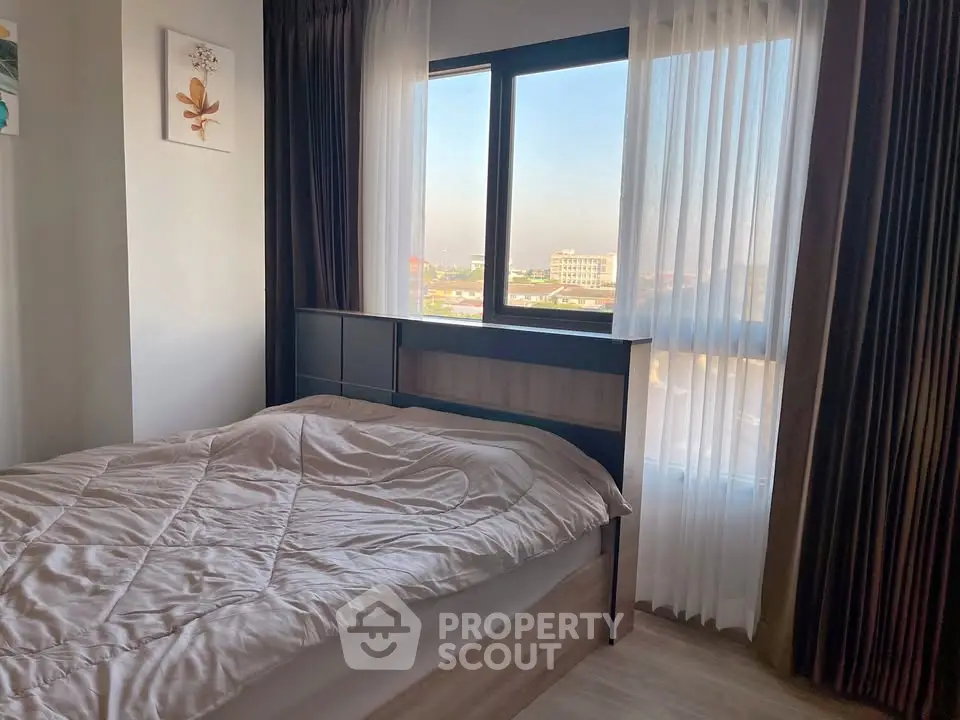 Cozy bedroom with large window offering a stunning city view, perfect for relaxation and comfort.