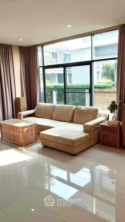 Spacious living room with large windows and modern beige sofa in a stylish apartment.