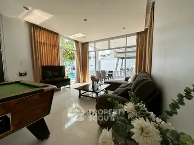 Spacious living room with pool table and large windows overlooking a patio, perfect for entertainment.