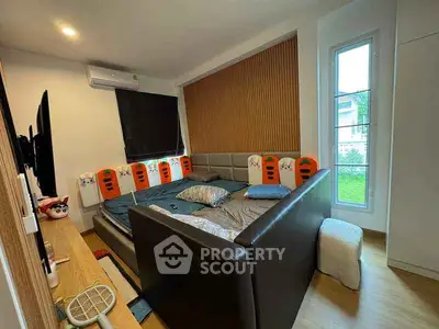 Spacious bedroom with modern decor and large window offering natural light