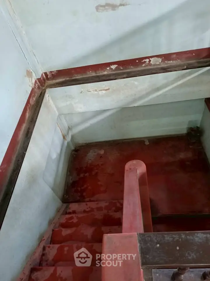 Rustic staircase with red steps and worn walls, ideal for renovation projects.