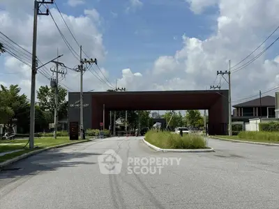 Modern residential entrance with sleek design and lush greenery under a clear blue sky.