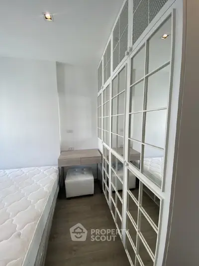 Modern minimalist bedroom with a large white bed, sleek built-in shelving units, and a cozy ambiance, perfect for urban living.