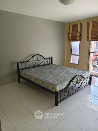 Spacious bedroom with elegant metal bed frame and large windows for natural light.