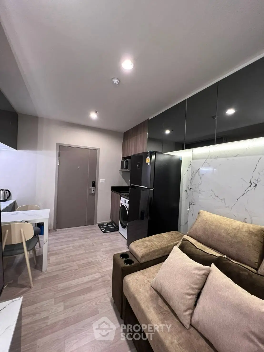 Modern living room with sleek kitchen, cozy sofa, and stylish decor in a contemporary apartment.
