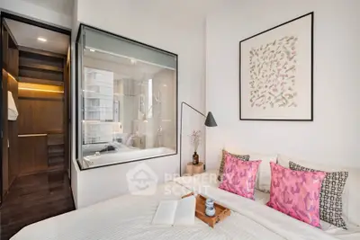 Modern bedroom with stylish decor and glass wall overlooking a luxurious bathroom.