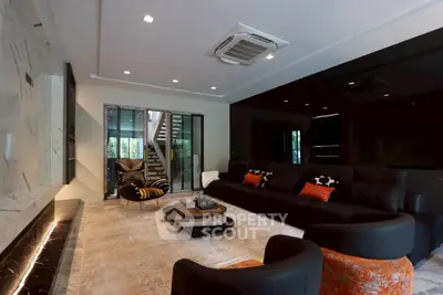 Luxurious modern living room with elegant black and orange decor, spacious seating, and stylish lighting.