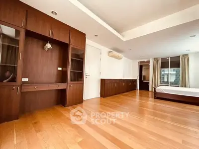Spacious bedroom with wooden flooring and built-in cabinets in modern apartment.