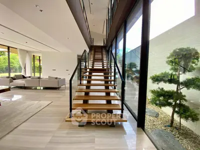 Luxurious modern home interior with elegant staircase and large windows overlooking a serene garden.