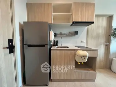 Modern compact kitchen with sleek appliances and wooden cabinetry in a stylish apartment.