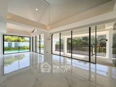 Spacious modern living room with floor-to-ceiling windows and pool view