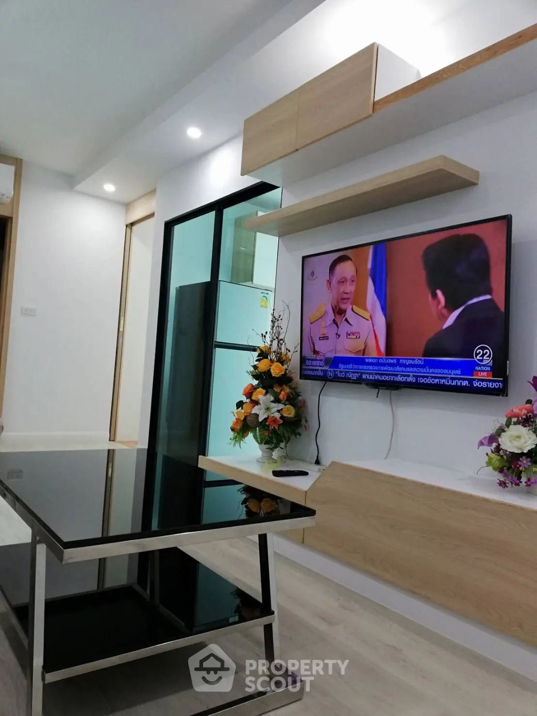 Modern living room with sleek black glass table and wall-mounted TV in stylish apartment.