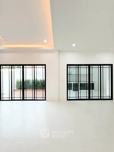 Spacious modern living room with large sliding glass doors and elegant ceiling lighting.