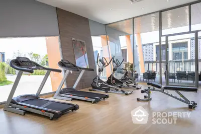 Modern gym with state-of-the-art equipment and floor-to-ceiling windows in luxury residential complex.