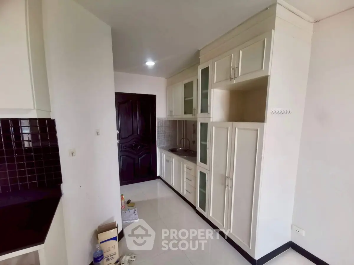 Modern kitchen with sleek cabinetry and black tile backsplash in a compact layout.