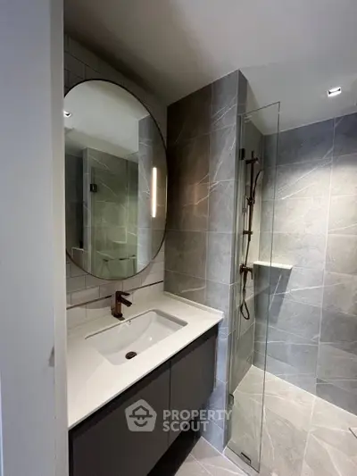 Modern bathroom with sleek design, featuring a large mirror and glass shower enclosure.