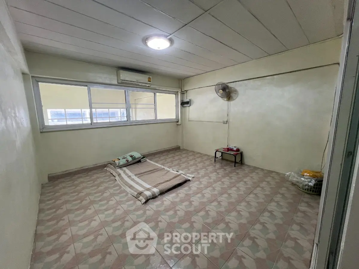 Minimalist bedroom with tiled flooring and large window, featuring a ceiling fan and air conditioning.