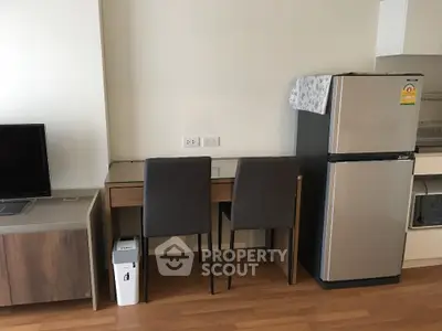 Modern apartment interior with fridge, TV, and dining area