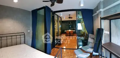 Modern bedroom with industrial design and glass partition leading to dining area.