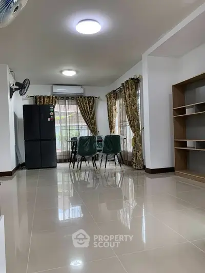 Spacious living area with dining set and modern fridge, featuring elegant curtains and ample natural light.