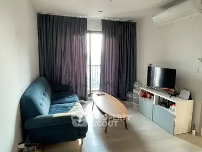 Modern living room with blue sofa, TV, and balcony view in a bright apartment.