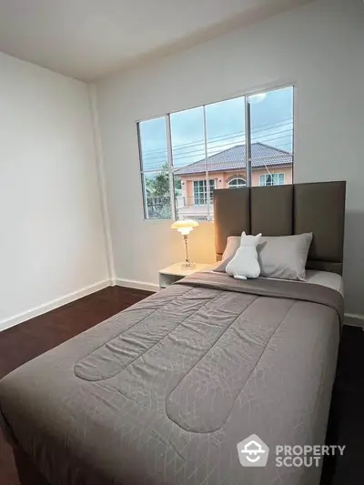 Cozy bedroom with single bed and large window offering natural light