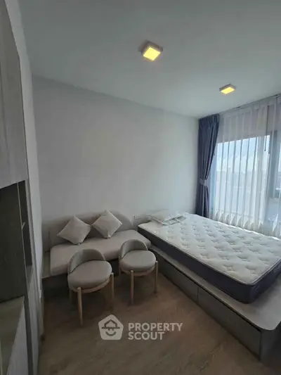Modern bedroom with minimalist design, featuring a cozy bed and stylish seating area, perfect for relaxation.