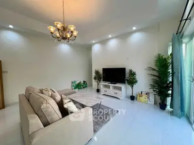 Spacious living room with elegant chandelier and modern decor in a bright apartment.