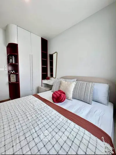 Modern bedroom with stylish decor and built-in storage, featuring a cozy bed and elegant mirror.