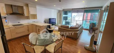 Modern open-plan living room with city view, featuring stylish kitchen and cozy seating area.