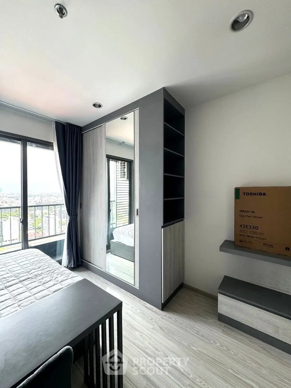 Modern bedroom with sleek furniture and city view from balcony