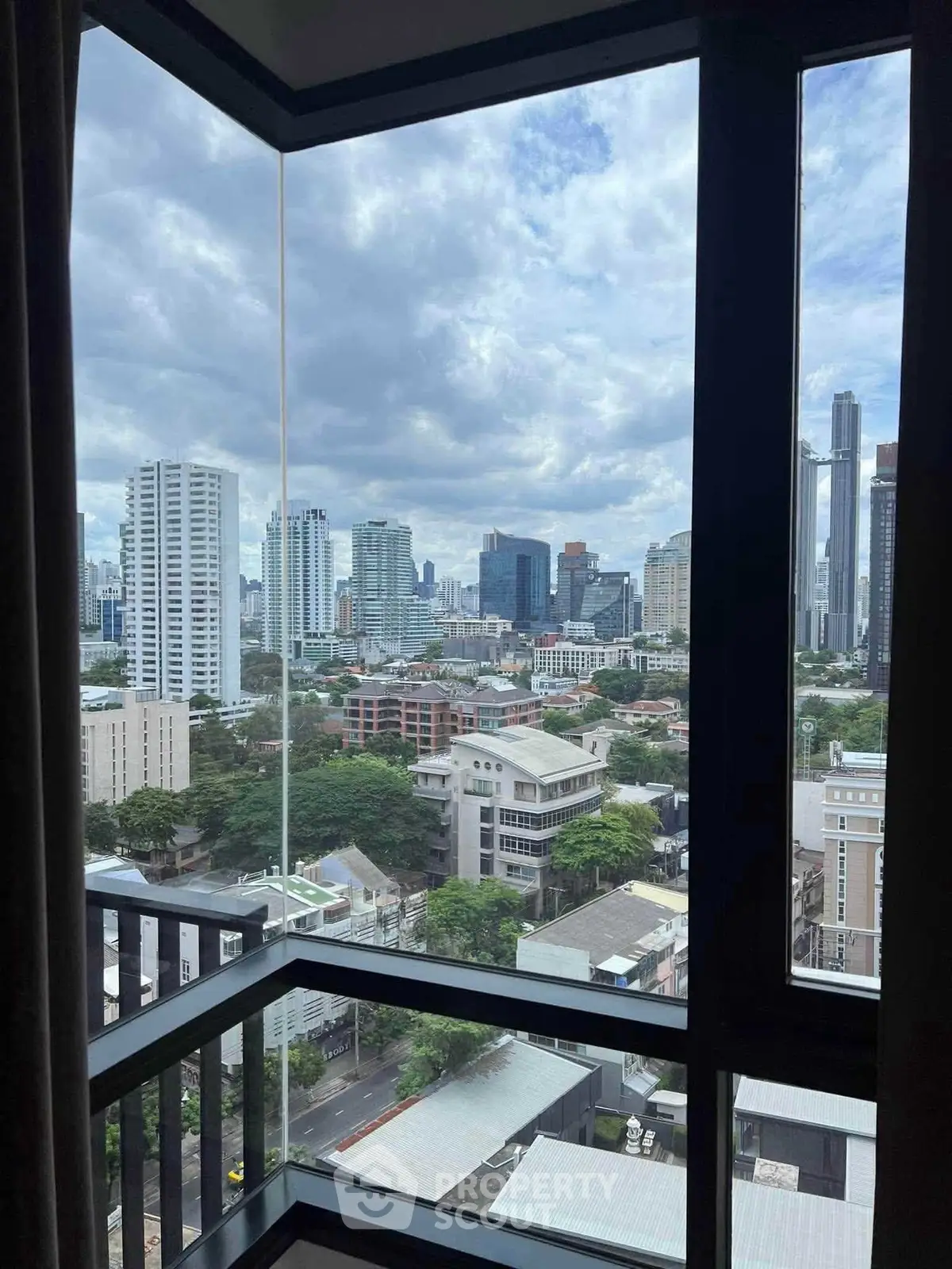 Stunning cityscape view from a high-rise apartment window, showcasing urban skyline and lush greenery.