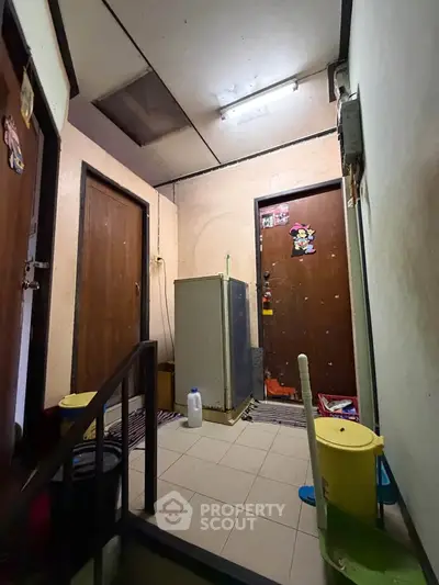 Compact apartment hallway with two doors and a refrigerator, showcasing a cozy living space.