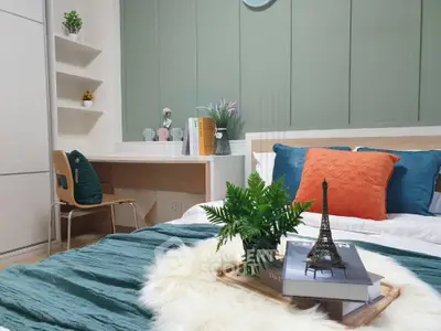 Stylish bedroom with modern decor, featuring a cozy bed, study area, and elegant green accent wall.