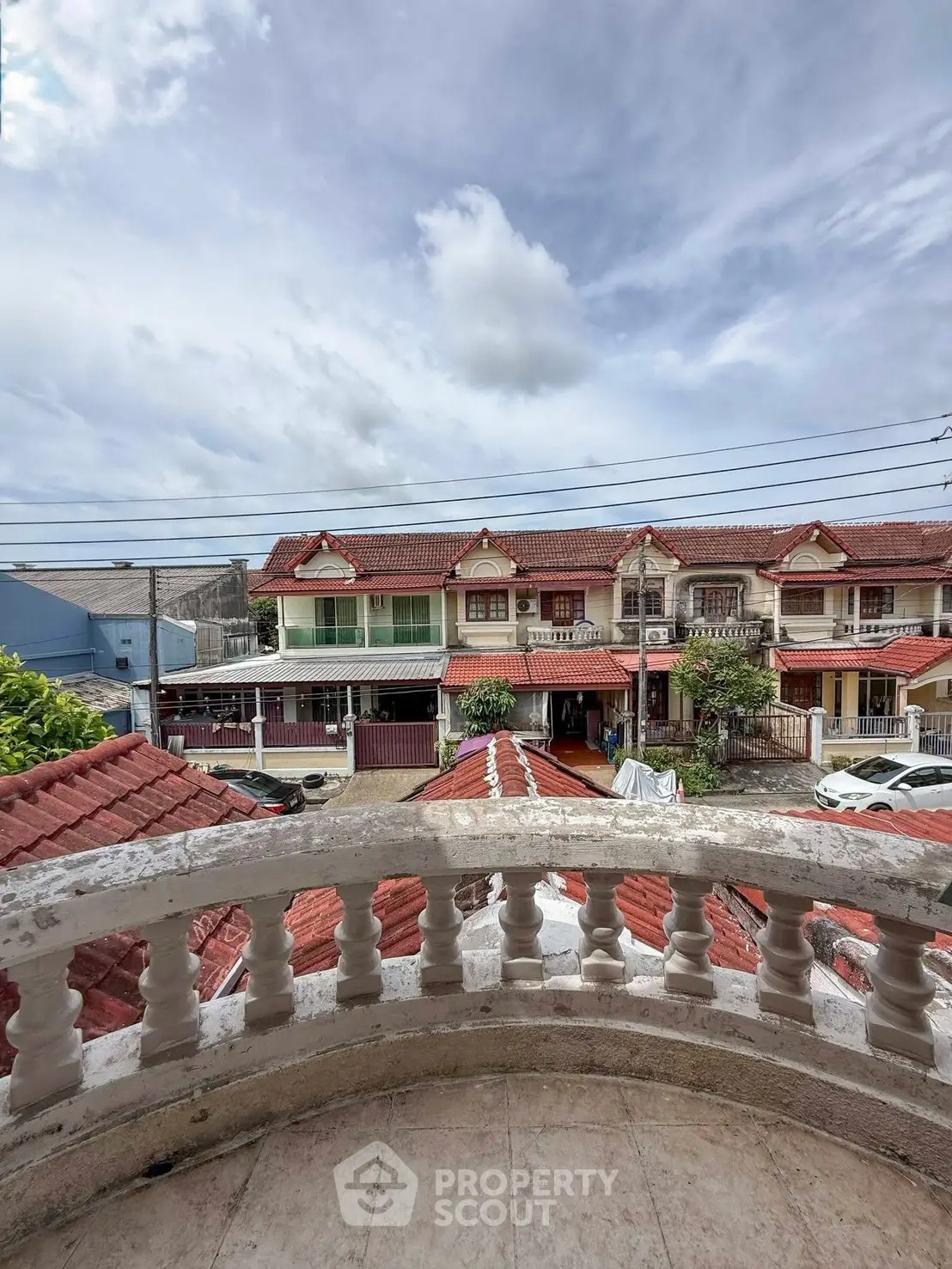 Charming balcony view of picturesque red-roofed townhouses under a bright blue sky.
