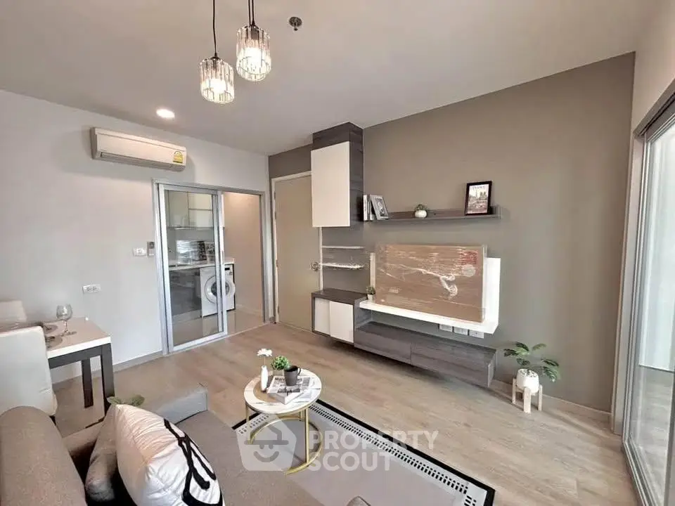 Modern living room with stylish decor and open kitchen view, featuring sleek furniture and natural lighting.