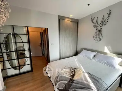 Modern bedroom with stylish decor and ample natural light, featuring a unique wall art and cozy bedding.
