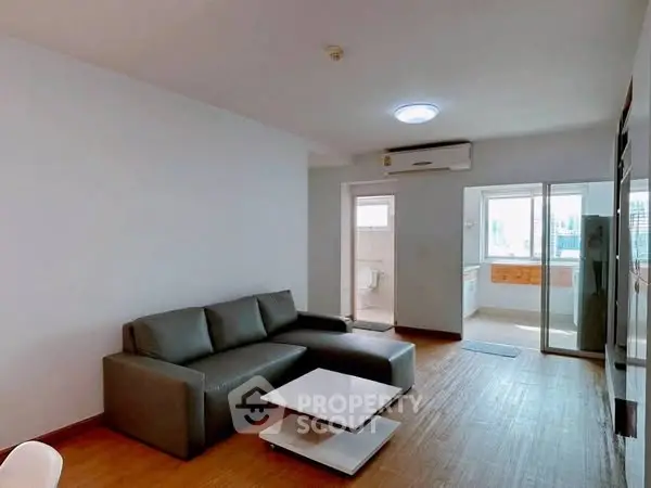 Modern living room with sleek sofa and open kitchen layout in a bright apartment.