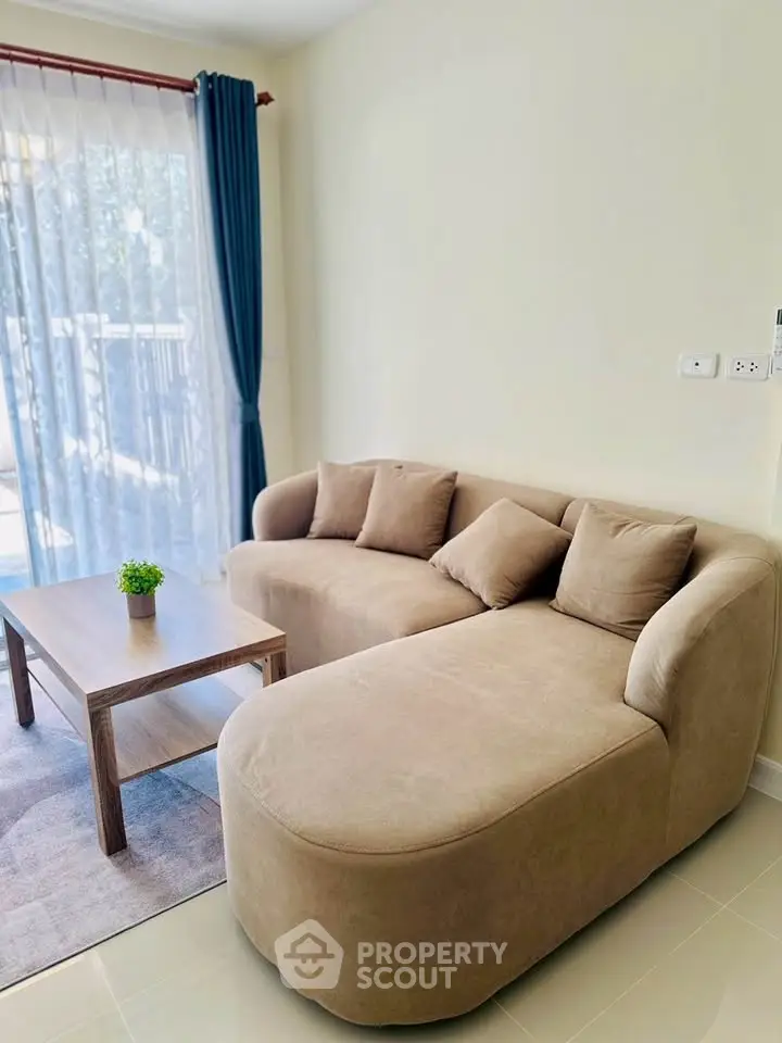 Cozy living room with modern beige sofa and natural light from large window.