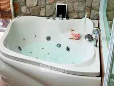 Luxurious bathroom with a modern jacuzzi tub and stone accent wall, perfect for relaxation.